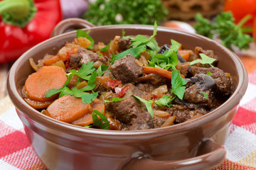 Stew with beef, vegetables and prunes in a saucepan, close-up