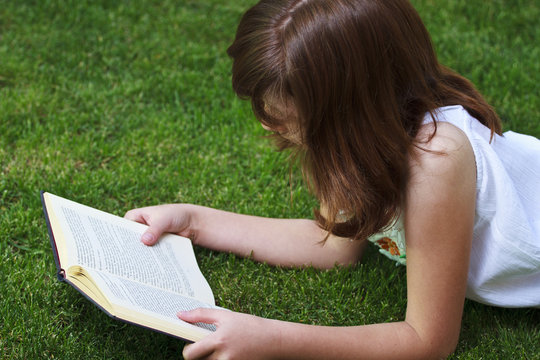Tale.Young beautiful girl reading a book outdoor