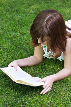 Idyllic.Young beautiful girl reading a book outdoor