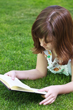 Idyllic.Young beautiful girl reading a book outdoor