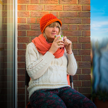Frau mit Becher Kaffee auf dem Balkon im Winter