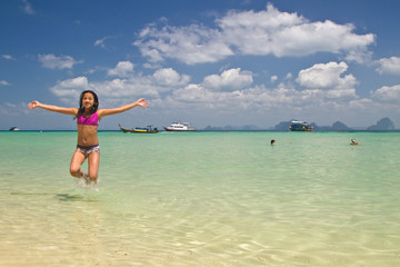Fototapeta na wymiar Girl jumping in the water at the beach of the Koh Ngai island Th