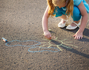 The child drawing a chalk on asphalt