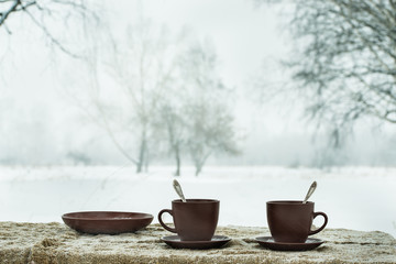 Two cups of tea on background of a winter landscape