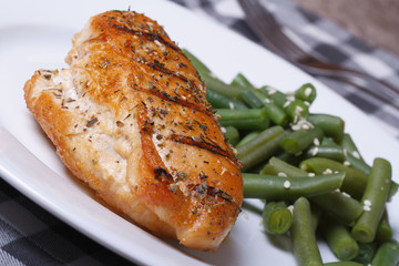 Grilled chicken meat with green beans on a white plate