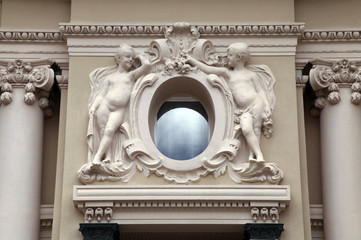 angel statues and oval window at baroque style facade