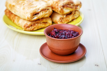 Cup with jam and sweet rolls on a table
