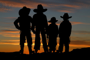 Beautiful silhouette of four young cowboys with a sunset backgro