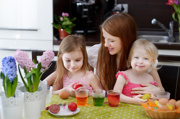 Mother and her daughters painting Easter eggs