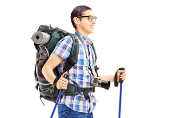 Young male tourist walking with hiking poles