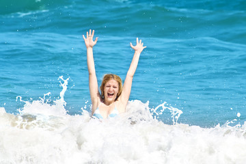 Young woman jumping in the waves on a tropical beach