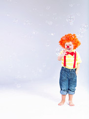 Funny picture of little clown making huge soap bubbles