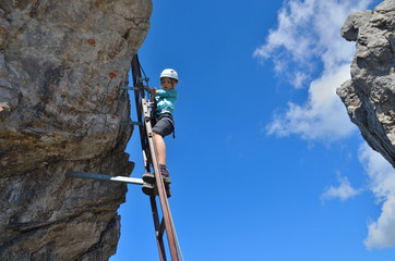 Kind beim Klettern auf Leiter im Klettersteig