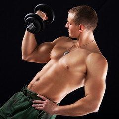 Fototapeta na wymiar Young muscular man lifts a weight with biceps.