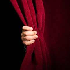 Hand appearing beneath the curtain.