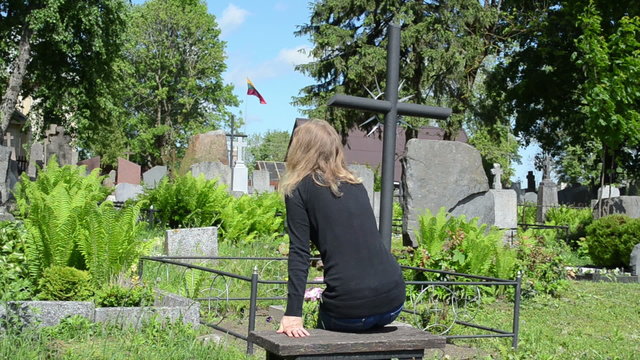 girl sit near soldier boyfriend grave. Lithuania national flag