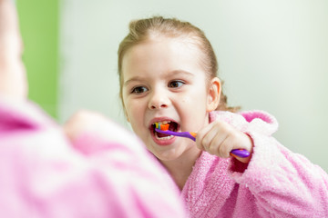 kid girl brushing teeth in bathroom