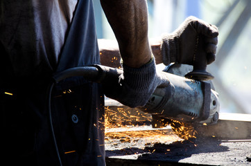Worker grinding a metal plate.