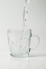 Obraz na płótnie Canvas Clear water pouring into a glass cup