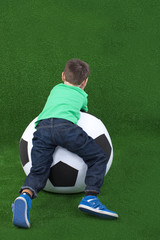 Kleiner Junge liegt auf Fußball von hinten - boy on soccer ball