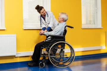Cheerful young nurse woman with senior man in wheelchair