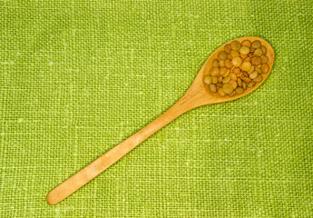 Lentils in spoon on green leaf