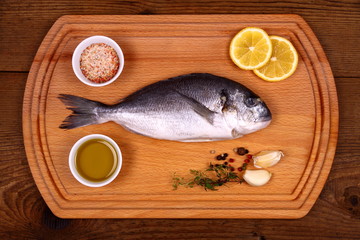 Fresh bream fish on cutting board with ingredients