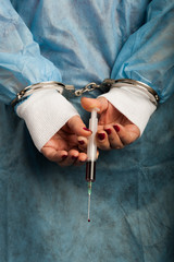 Criminal handcuffed medical person with bloody injector in hand
