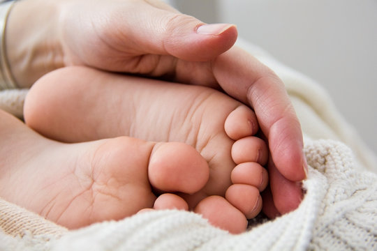 A mother holding the feet of her baby son
