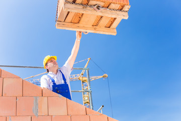 Maurer bekommt eine Palette Backsteine auf Baustelle