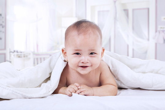 Baby laughing under blanket inside the house