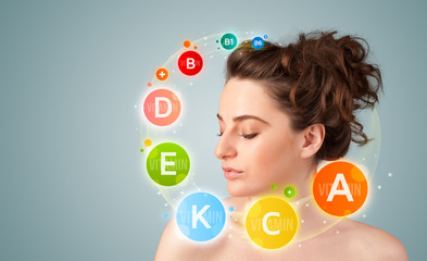 Pretty young girl with colorful vitamin icons and symbols