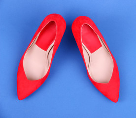 Beautiful red female shoes, on blue background