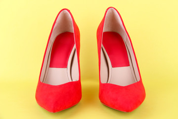 Beautiful red female shoes, on yellow background