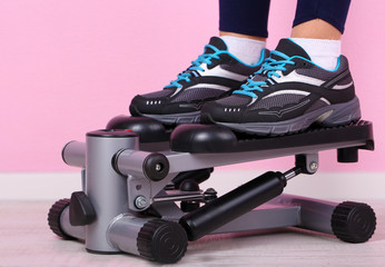 Woman doing exercise on stepper. Close-up on legs.