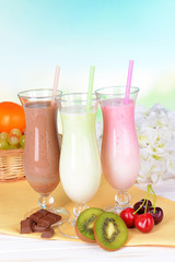 Milk shakes with fruits on table on light blue background
