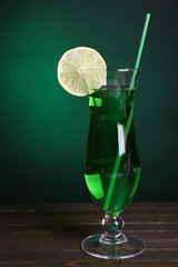 Glass of cocktail on table on dark green background