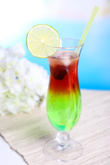 Glass of cocktail on table on light blue background