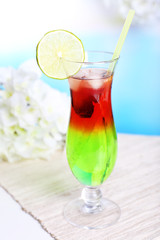 Glass of cocktail on table on light blue background