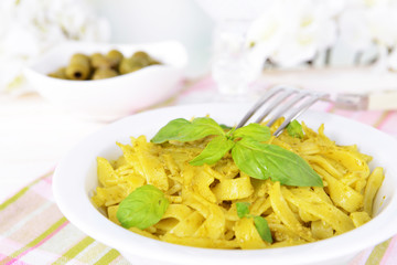 Delicious pasta with pesto on plate on table on light