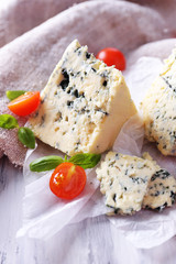 Tasty blue cheese with tomatoes and basil on paper