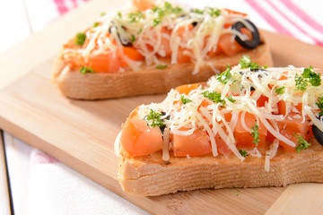 Delicious bruschetta with tomatoes on cutting board close-up