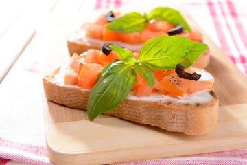 Delicious bruschetta with tomatoes on cutting board close-up