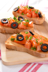 Delicious bruschetta with tomatoes on cutting board close-up