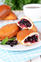 Fresh baked pasties with currant on plate on table close-up