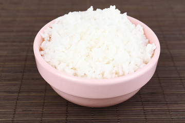 Cooked rice in bowl on bamboo background