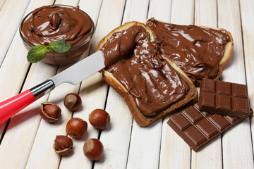Bread with sweet chocolate hazelnut spread on wooden background