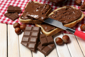Bread with sweet chocolate hazelnut spread on wooden background