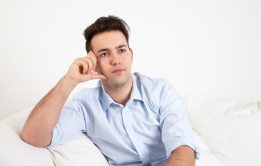 Junger Mann auf dem Sofa überlegt