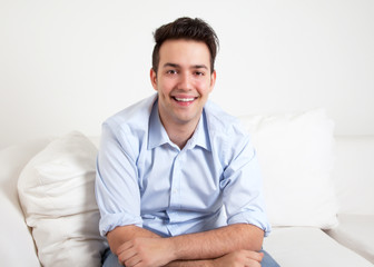 Lachender junger Mann auf dem Sofa